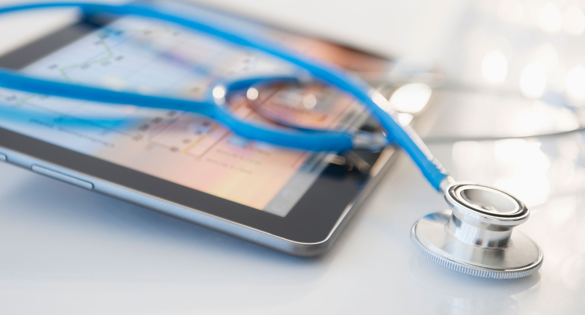 An iPad and stethoscope laying on a table.