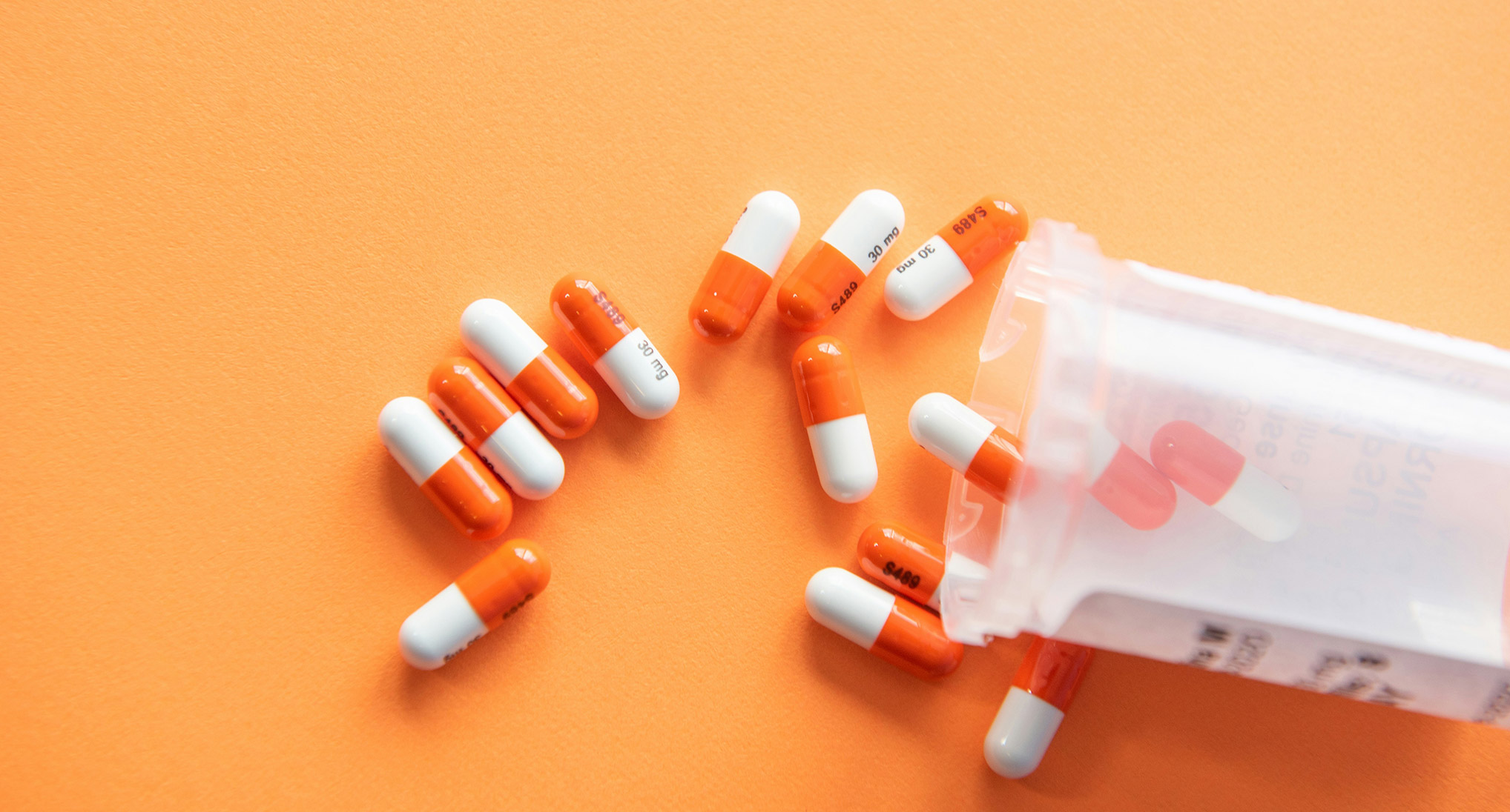 Prescription medication spilling out of a pill canister.